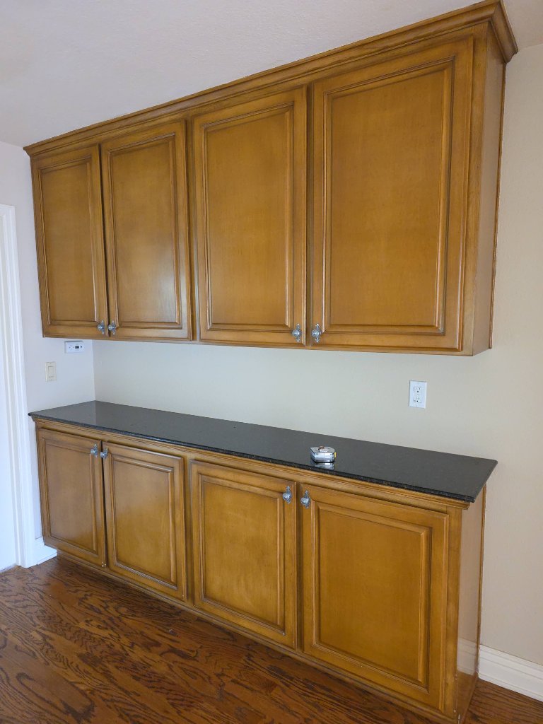 Old yellow cabinets with dark countertop before remodel