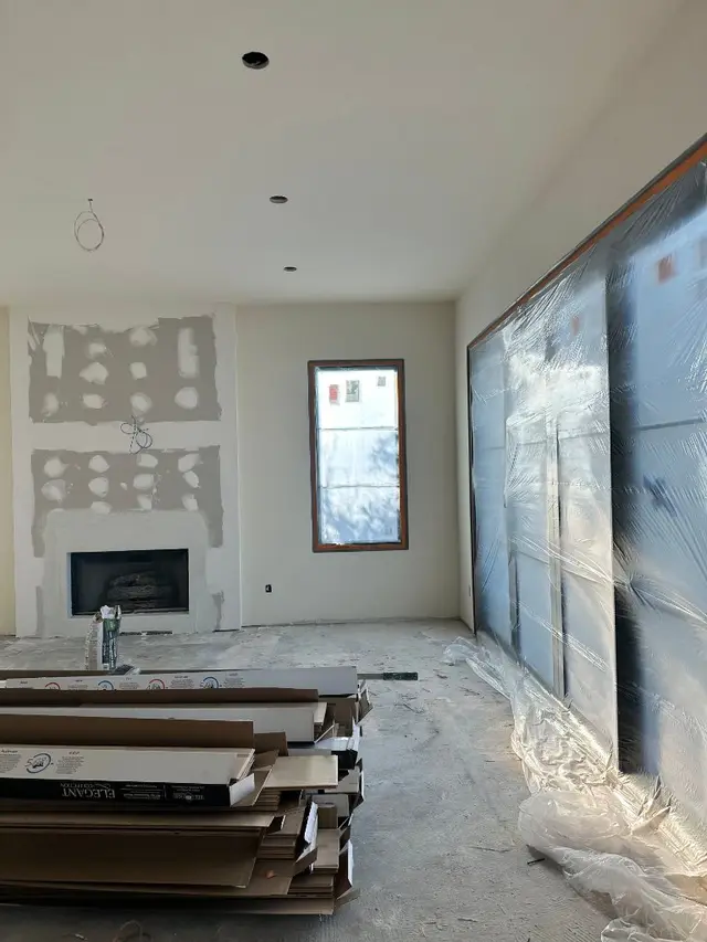 Interior painting in progress — living room with fireplace and covered sliders Los Angeles