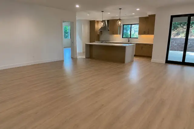Open-concept living room and kitchen with finished light wood flooring Los Angeles